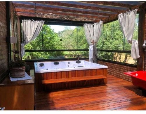 een grote badkamer met een bad voor een raam bij Recanto das Pipas - Hospedagem Diferenciada in São Valentim do Sul