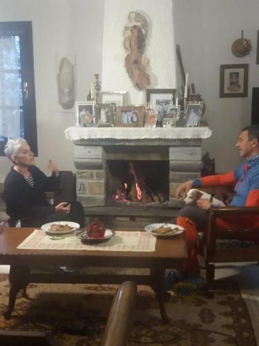 a group of people sitting in a living room with a fireplace at Dimosthenis Karastamatis Rooms in Xorychti