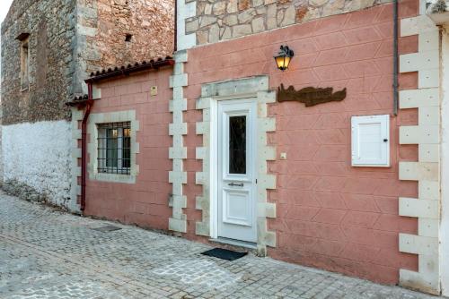 a red brick wall with a white door on a building at Aroni Cretan comfortable house - Hamam suites Aroni in Arónion