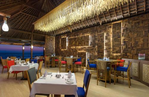 a restaurant with tables and chairs with the ocean in the background at The Chandi Boutique Resort & Spa in Senggigi