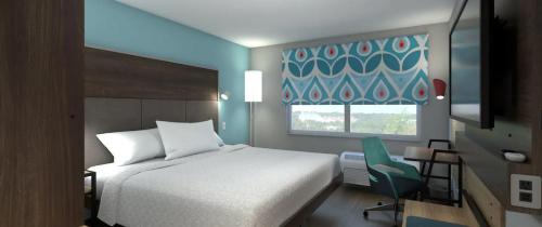 a bedroom with a bed and a chair and a window at Tru By Hilton Manteca in Manteca