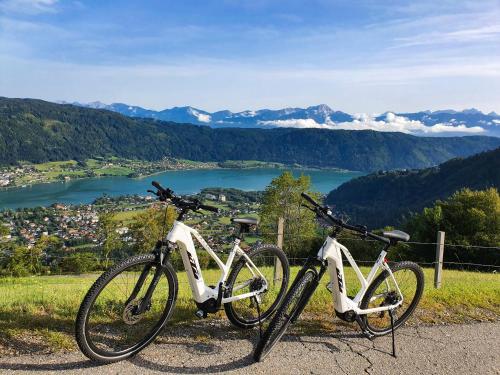 two bikes parked on top of a hill overlooking a lake at Kozma Apartments Peterlewand Gerlitzen Ossiachersee in Bodensdorf