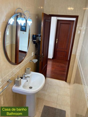 a bathroom with a sink and a mirror and a door at Villa Kethellen in Porto Covo