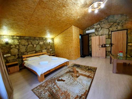 a bedroom with a bed and a stone wall at Guest house Ijevan's Garden in Ijevan