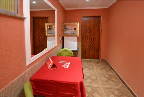 a red table with a green chair in a room at Caravellas Hotel in Rio de Janeiro