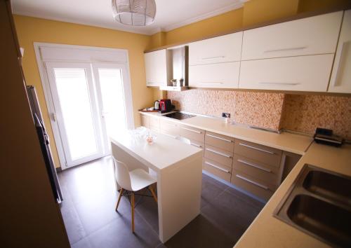 a kitchen with white cabinets and a white table at Rooftop privé - your comfort apartment in Korçë