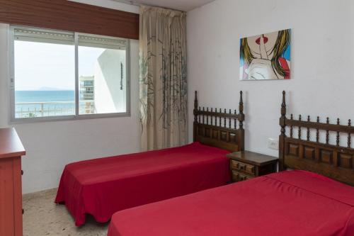 een slaapkamer met twee rode bedden en een raam bij Florazar 1, Iii-B 8-B in Cullera