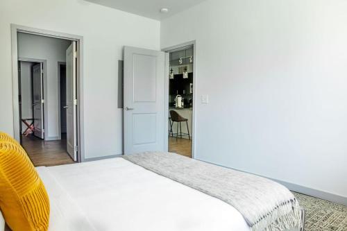 a bedroom with a white bed with a yellow chair at Placemakr Music Row - Vanderbilt in Nashville