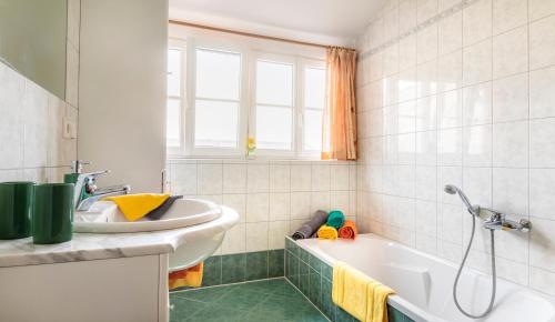 ein weißes Badezimmer mit einer Badewanne und einem Waschbecken in der Unterkunft Vorderreithbauer in Hof bei Salzburg