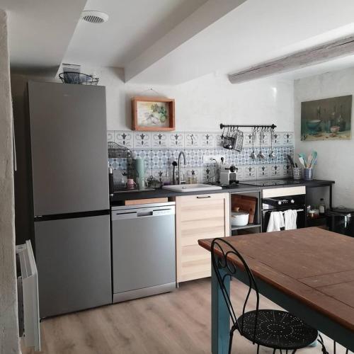 une cuisine avec un réfrigérateur en acier inoxydable et une table dans l'établissement La Maison Du Parc RDC, à Balaruc-les-Bains