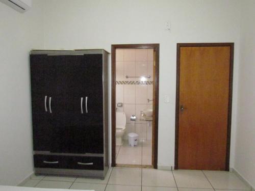 a bathroom with a toilet and a door to a bathroom at RECANTO DAS ARARAS in Olímpia