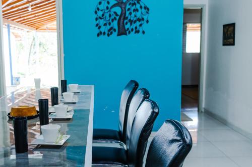 uma mesa com cadeiras pretas e uma parede azul em Sítio com SPA, lareira e piscina - Piranguinho, MG em Piranguinho