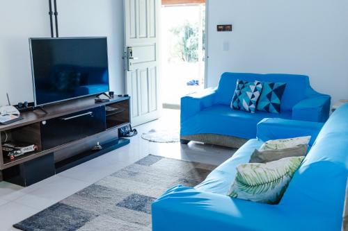 a living room with blue couches and a flat screen tv at Sítio com SPA, lareira e piscina - Piranguinho, MG in Piranguinho
