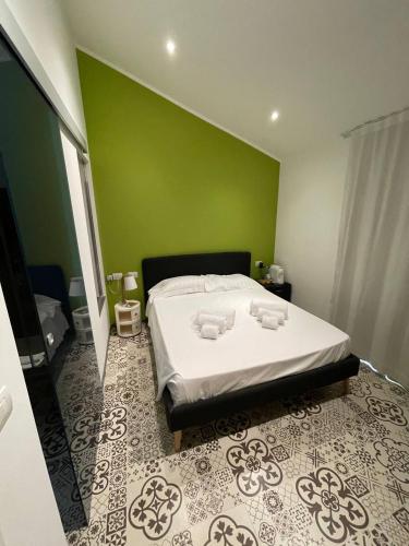 a bedroom with a large bed with a green wall at Gaias Rooms in Olbia