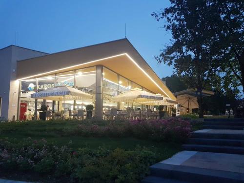 un bâtiment avec des tables et des parasols devant lui dans l'établissement Family Panzió Zalakaros, à Zalakaros