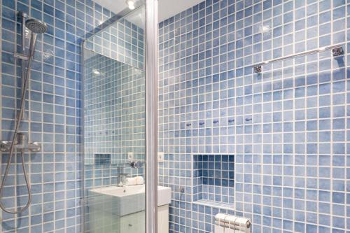uma casa de banho em azulejos azuis com um chuveiro e um lavatório. em LLAFRANC 100 % (c/Llevant) em Llafranc