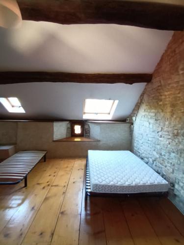 Cette chambre dispose d'un lit et d'un banc sur du parquet. dans l'établissement Prieuré Saint Marcel, à Fleurey-sur-Ouche