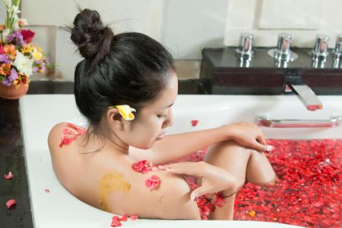 a young woman sitting in a bath tub with red flowers at The Astari Villa and Residence in Jimbaran