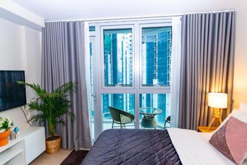 a bedroom with a bed and a large window at Holiday suite at Uptown Parksuites II Uptown BGC in Manila