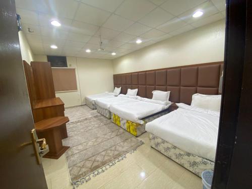 a hotel room with three beds and a chalk board at شقق أجياد السد in Mecca