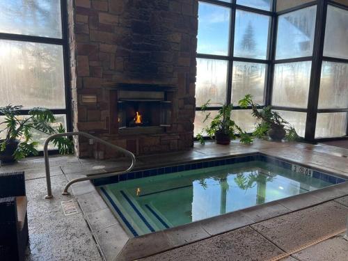 a swimming pool in a room with a fireplace at King Bed Condo at Cedar Breaks Lodge in Brian Head