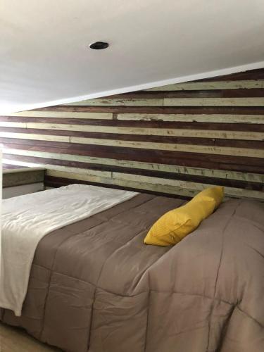 a bed with a yellow pillow on top of it at Azul en Lavalle 4 in Azul