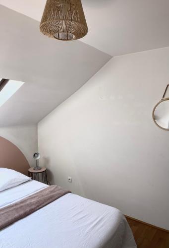 une chambre avec un lit et un mur blanc dans l'établissement Troisieme du nom, à Nevers