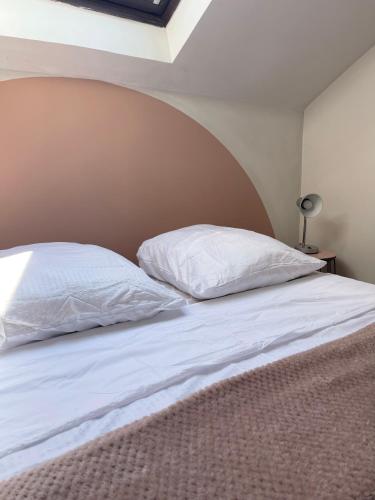 un lit avec deux oreillers blancs dessus dans l'établissement Troisieme du nom, à Nevers