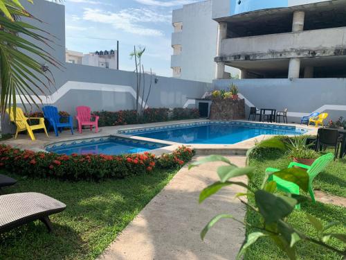 a swimming pool in a yard with colorful chairs at Hotel Jar8 Boca -Cerca WTC y plazas comerciales- in Veracruz