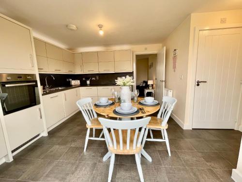 a kitchen with a wooden table with chairs and a dining room at Luxurious Beach House with spectacular sea views in Felixstowe