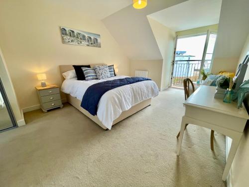 een slaapkamer met een bed, een bureau en een raam bij Luxurious Beach House with spectacular sea views in Felixstowe