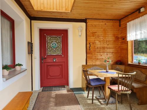 een rode deur in een kamer met een tafel bij Apartmenthaus Almwiese Flattnitz in Flattnitz