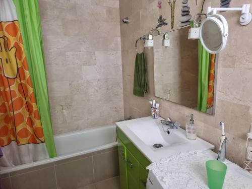 a bathroom with a sink and a mirror and a tub at Apartamento Ura in Morro del Jable