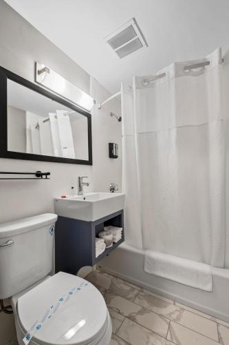 a bathroom with a toilet and a shower and a sink at Inn On Arsenal in Watertown