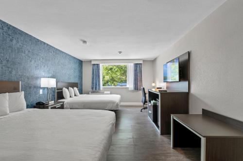 a hotel room with two beds and a desk at Inn On Arsenal in Watertown