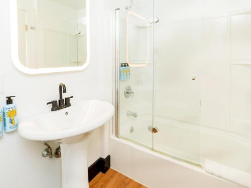 a white bathroom with a sink and a shower at Aqua by American Beech - Adults Only in Aquebogue