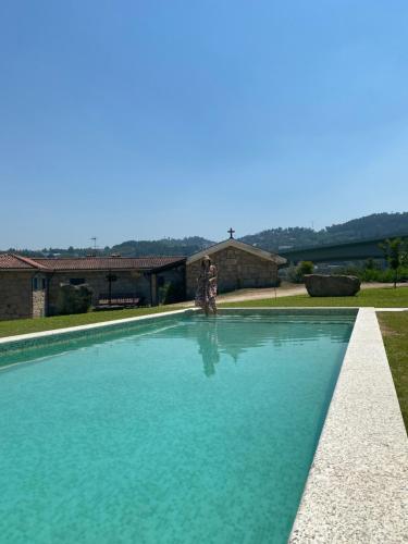 una persona in piedi accanto alla piscina di Quinta do Casarão by VinteOito - Casa de Campo com Piscina ad Amarante