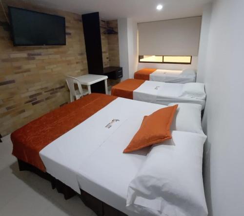 a room with four beds and a flat screen tv at Hotel San Lorenzo in Bucaramanga