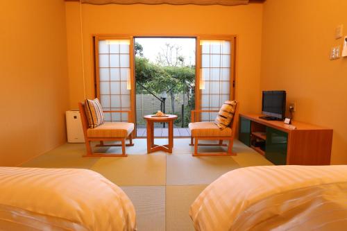a bedroom with two beds and a desk and a television at Oyado Ikegami in Uozu