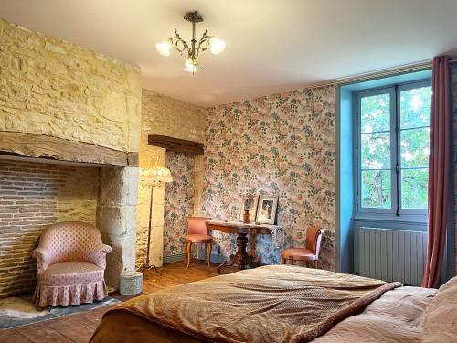 a bedroom with a bed and a fireplace and a desk at Le Clos Chalmon Chambre d'hôte in Montignac