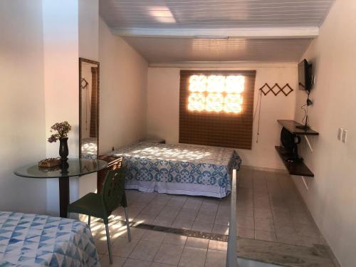 a room with a bed and a table and a window at Casalê in Lençóis