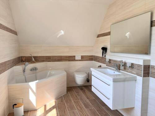 ein Badezimmer mit einer Badewanne, einem Waschbecken und einem WC in der Unterkunft Ferienhaus Svantovit - exklusives Ferienhaus mit Sauna, Whirlpool und Kamin in Putgarten