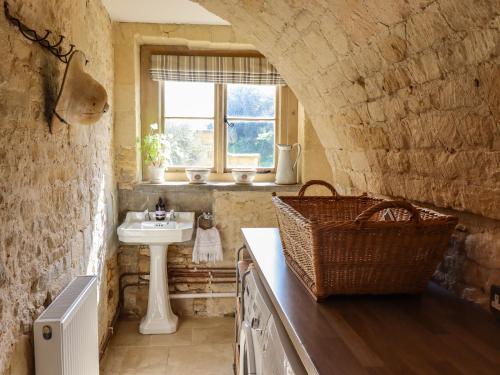 un bagno in pietra con lavandino e lavandino di The Compton Cottage a Cheltenham