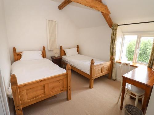 a bedroom with two beds and a desk and a window at The Nook in Stroud