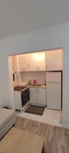 a small kitchen with white cabinets and a white refrigerator at Stan na dan "Sanski Most" in Sanski most