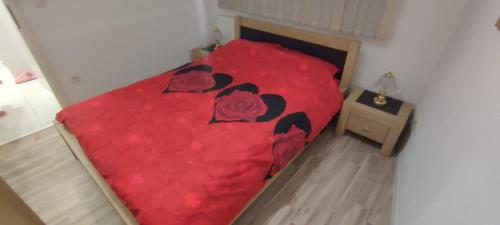 a bed with a red bedspread with roses on it at Stan na dan "Sanski Most" in Sanski most