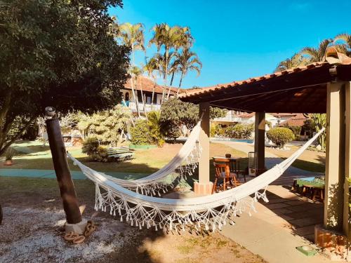 a hammock in a pavilion with a table and chairs at Pousada Chez Moi in Cabo Frio