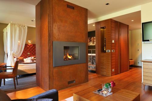 a living room with a fireplace and a bedroom at Hotel Balnea Superior - Terme Krka in Dolenjske Toplice