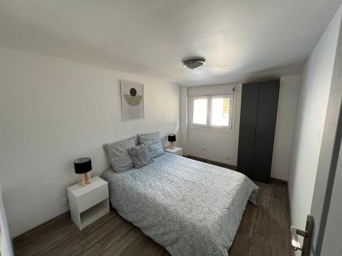 a white bedroom with a bed and a window at La Casa de Lacanau in Lacanau