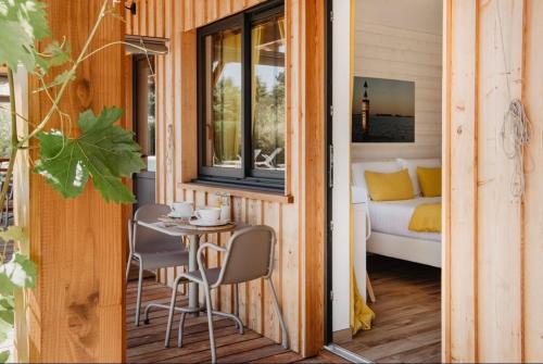 une petite maison avec une table et des chaises sur une terrasse couverte dans l'établissement La Cabane du Ferret, à Lège-Cap-Ferret
